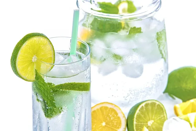 Szklanki lemoniady z miętą i owocami na drewnianym stole w plenerze